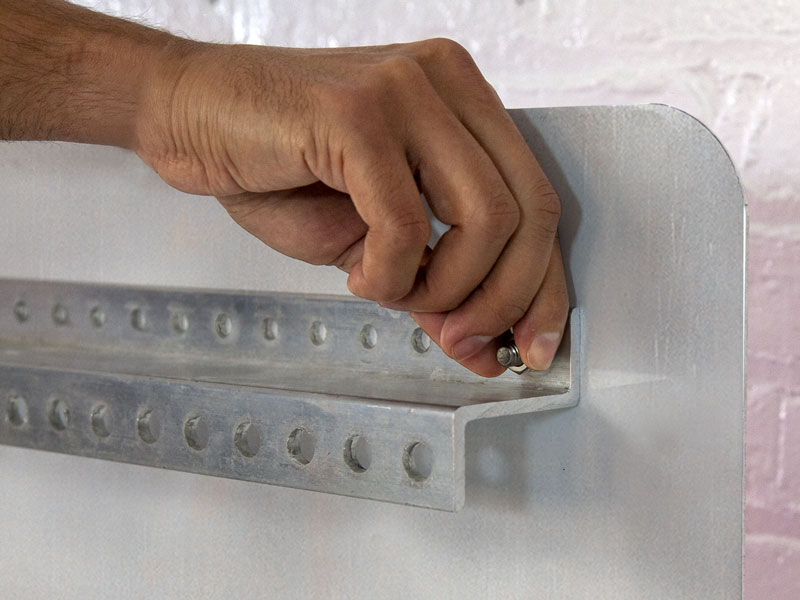 Person using bolts to attach the z-bar to a sign