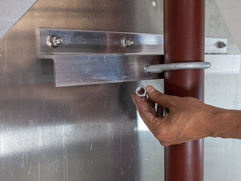 Person mounting a u-bracket around a pole and through the z-bar outer holes